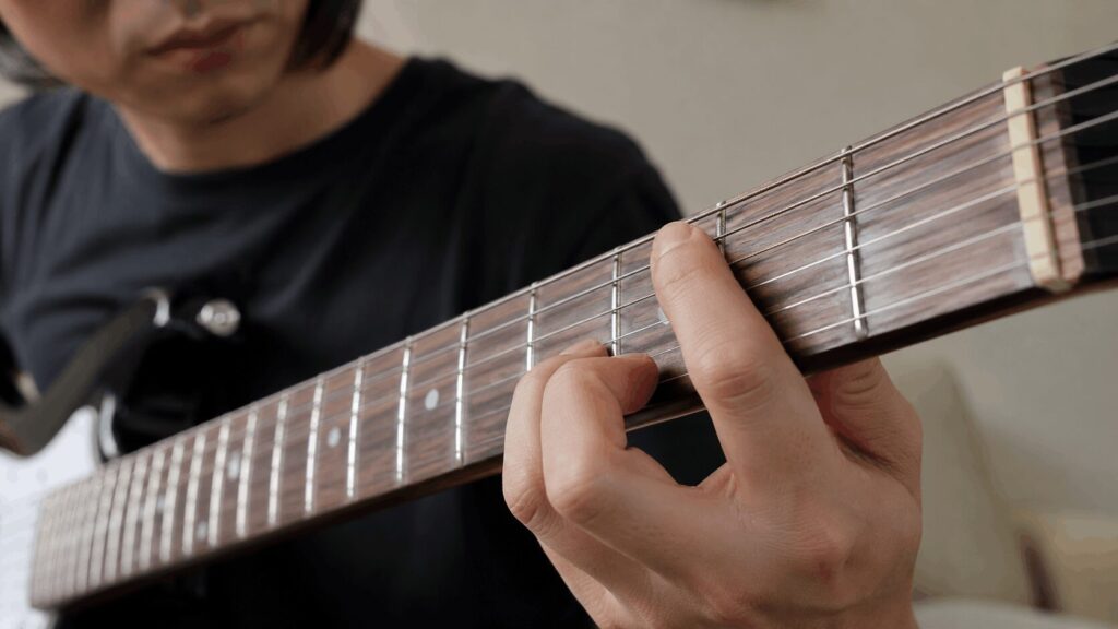 初心者がエレキギターの弦高や押さえにくさを確認している手元