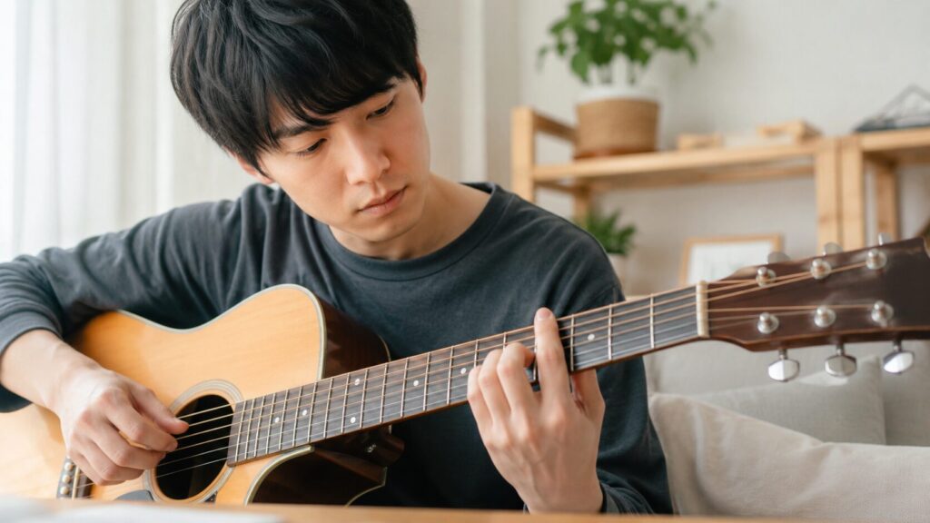 アコースティックギターのコードを練習する初心者の日本人男性