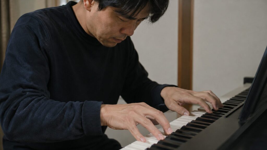 電子ピアノで両手の指使いを練習する日本人男性の手元