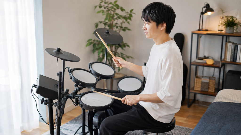初心者の日本人男性が自宅で電子ドラムを練習する様子