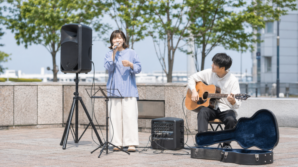 マイクとギターをPAスピーカーに接続して演奏する路上ライブのデュオ