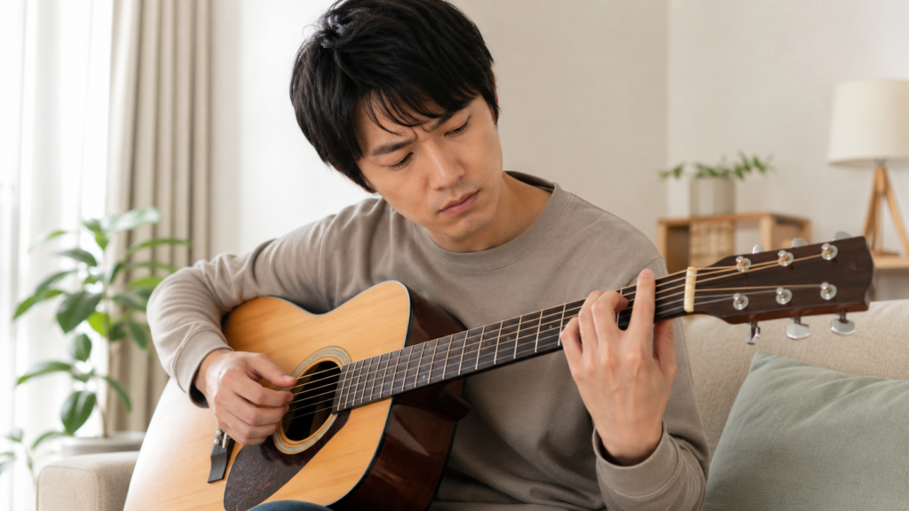 ギターのFコードを練習する日本人男性