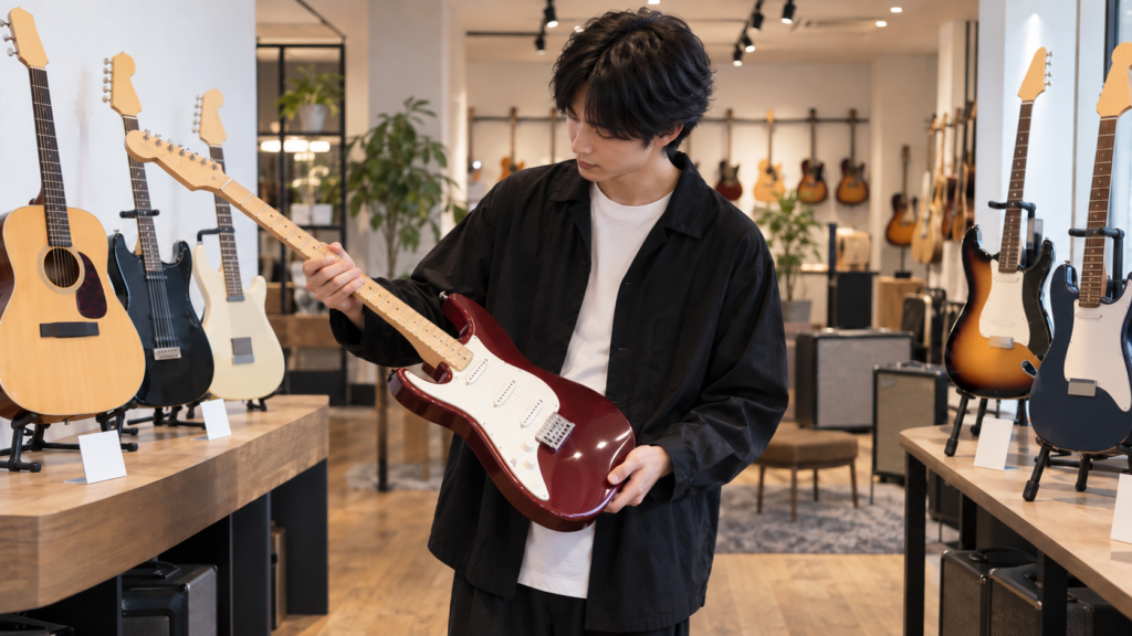 楽器店で左利き用ギターの弾きやすさを確認する男性